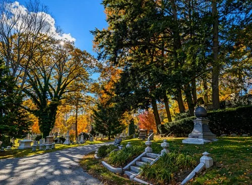 Scenic roadway through Jamaica Plain, MA cemeteries with historic monuments and autumn trees