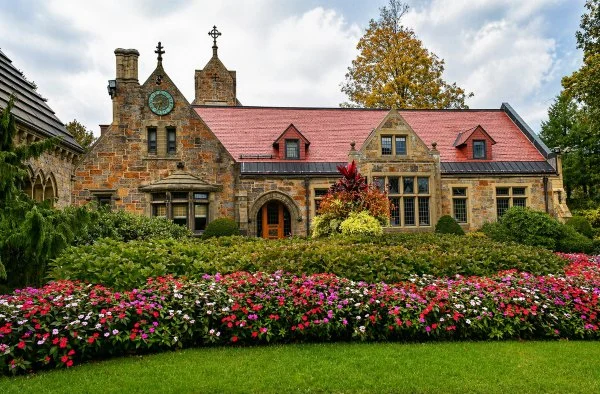 Historic stone building at Boston, MA cemeteries with red roof, clock tower, and flower gardens